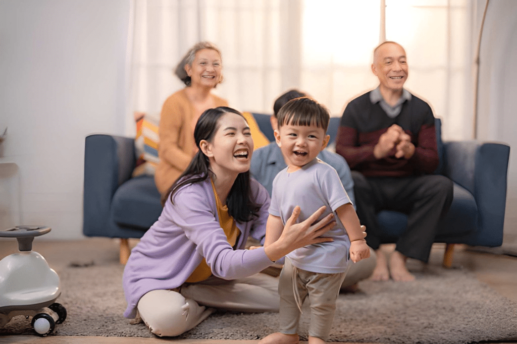 Mother smiling with toddler and family members in background