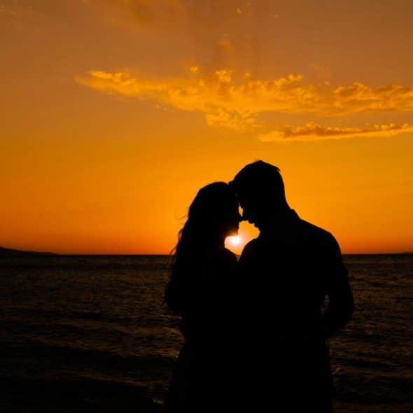 A couple in front of a sunset.