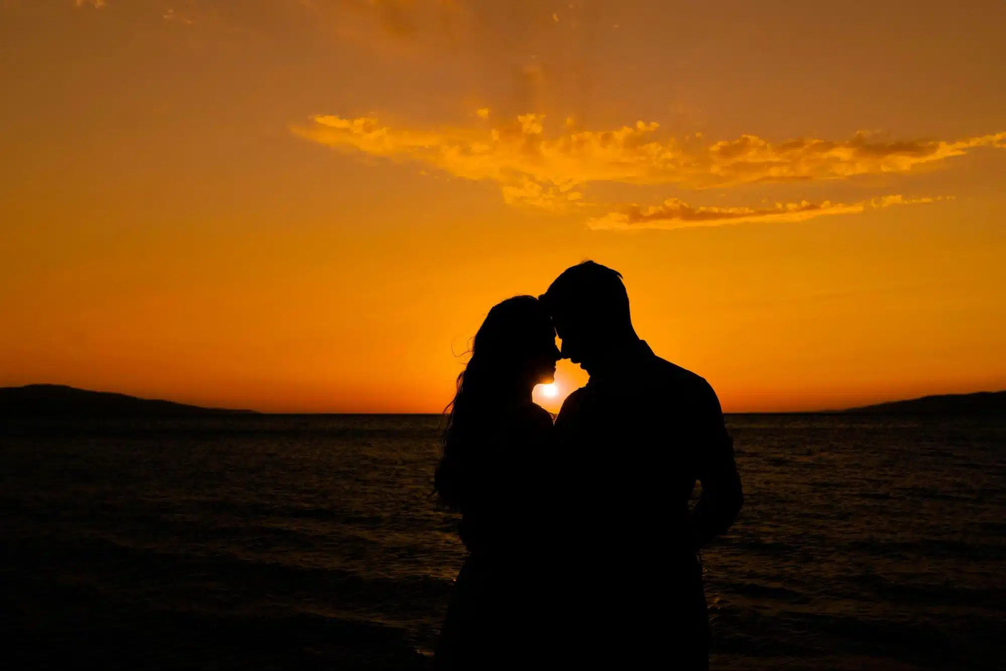 A couple in front of a sunset.