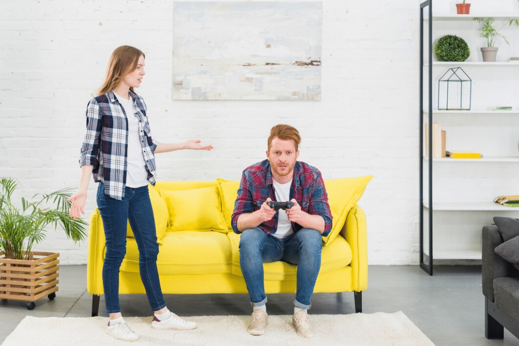Woman upset at man playing video games on couch