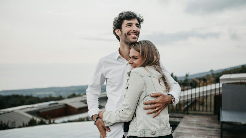 A couple hugging on the top of a building. 