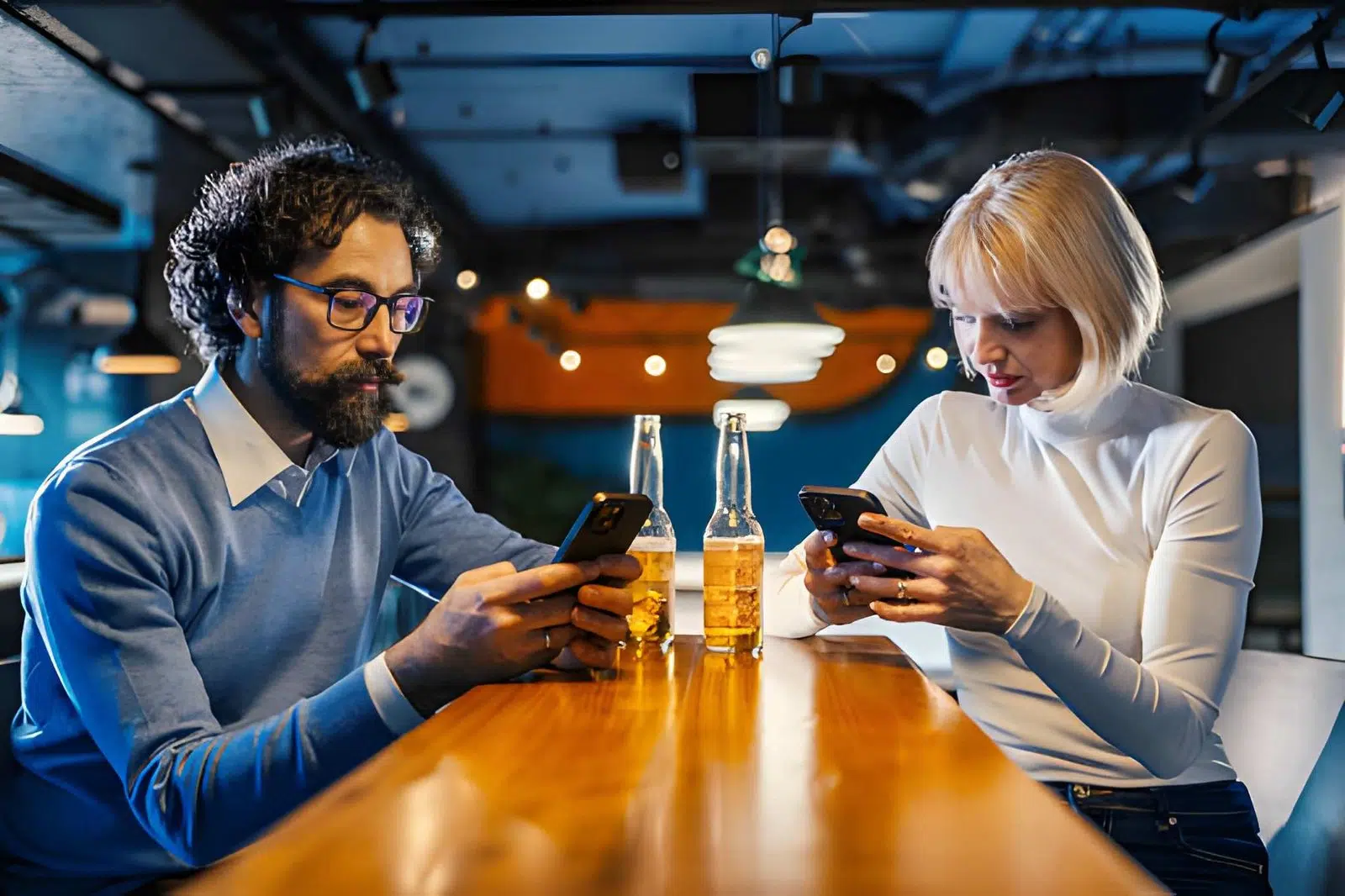 Couple sitting at a bar ignoring each other during a date
