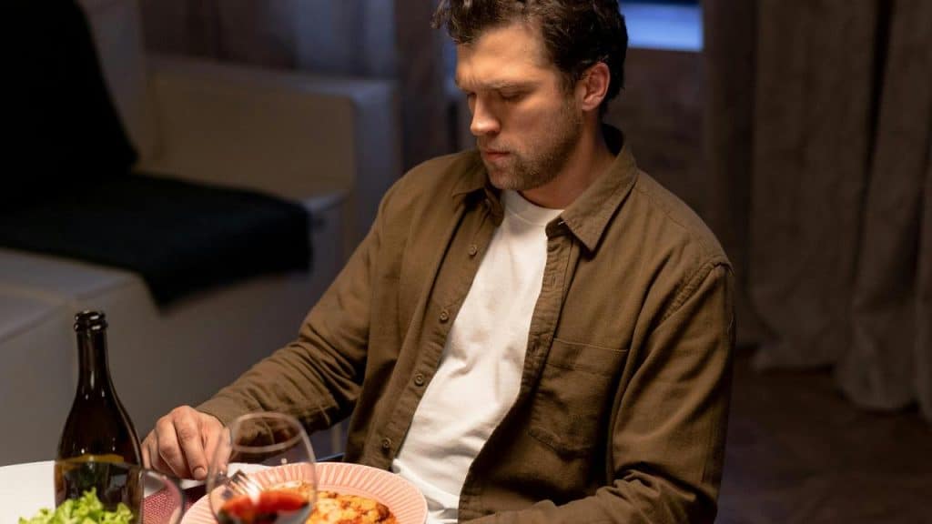 A man sitting at a table with food and a drink.