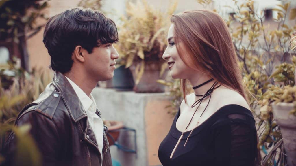 A man and a woman standing close are looking in the eyes of each other.