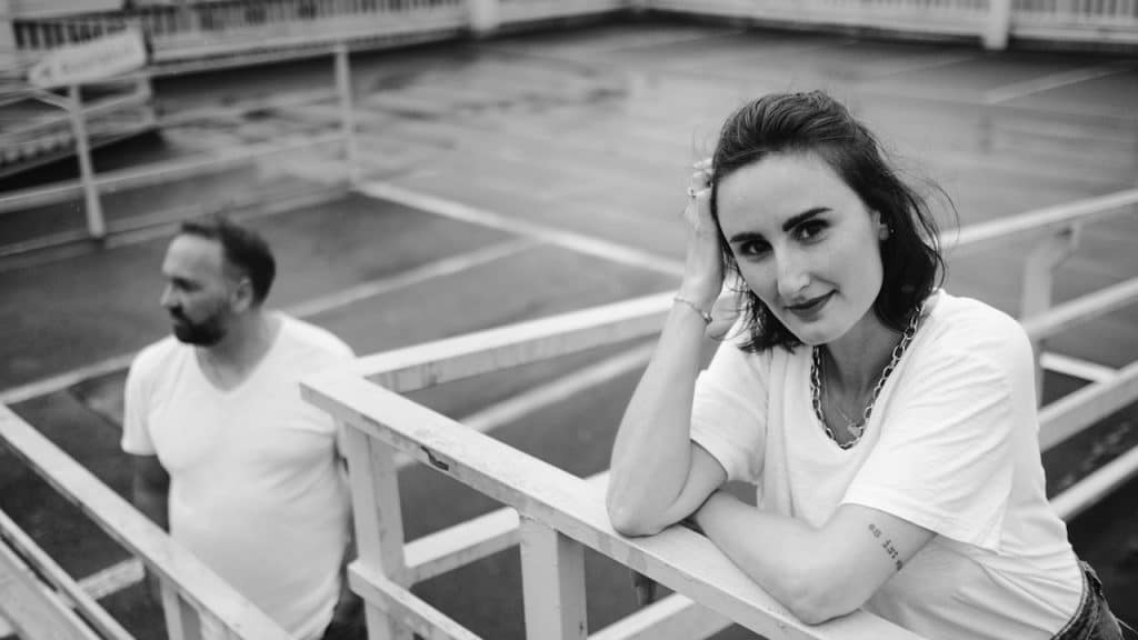 A woman in a white shirt is sitting on a white wooden bench.