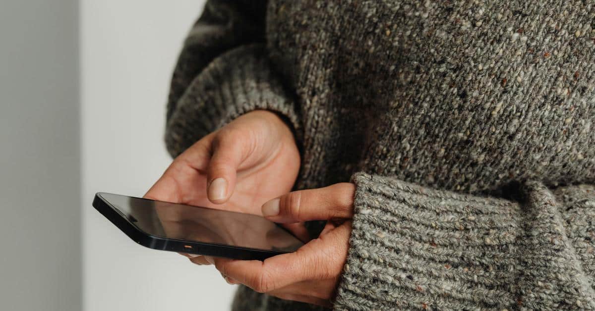 A person holding and using a smartphone with both hands.