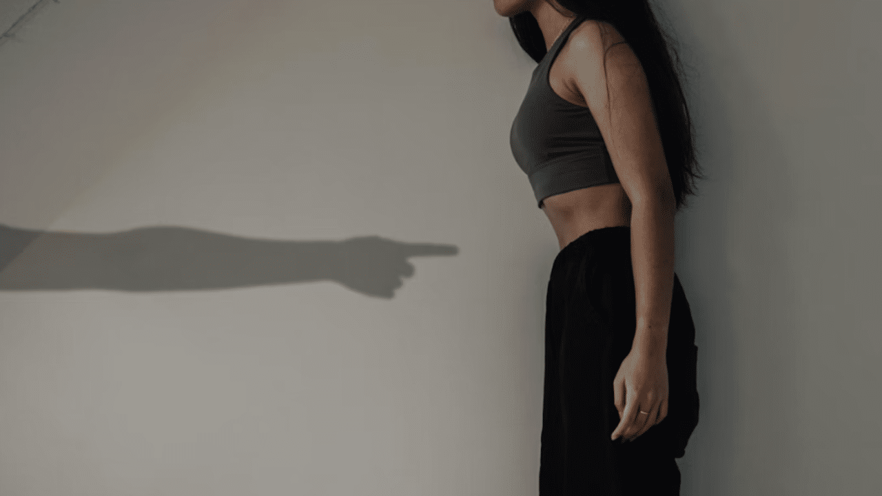 A manβs hand pointing at a womanβs stomach