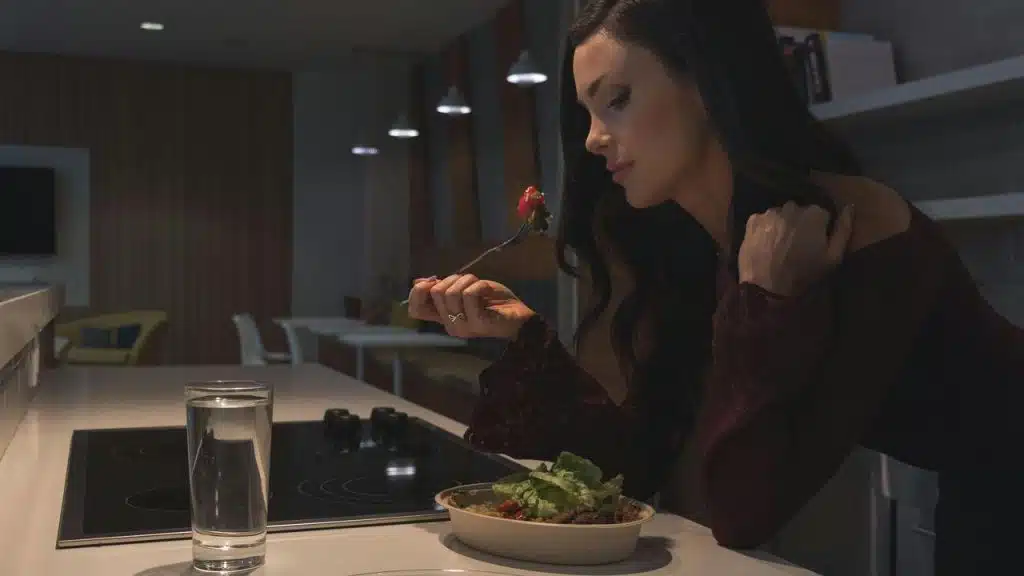 A woman sitting at a counter eating a salad.