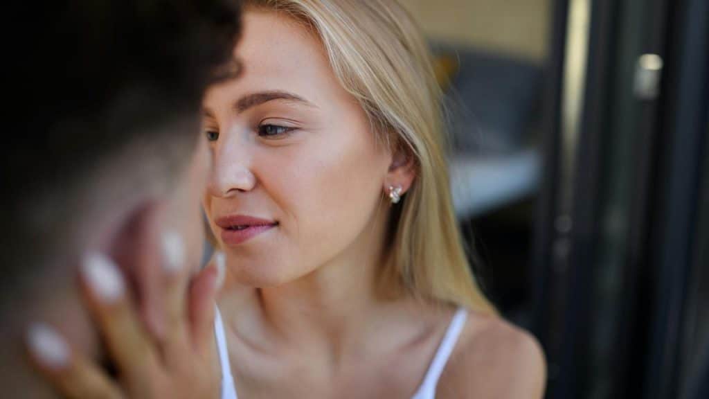 A woman stroking a man’s face.