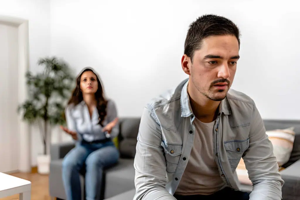 Distressed man ignoring his girlfriend behind him