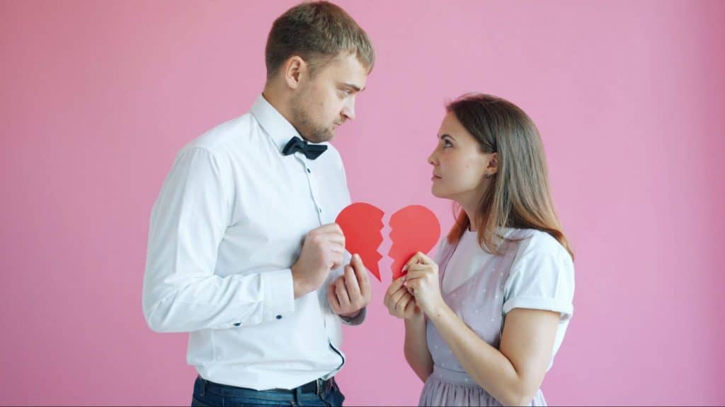 A man and woman holding heart shaped broken paper