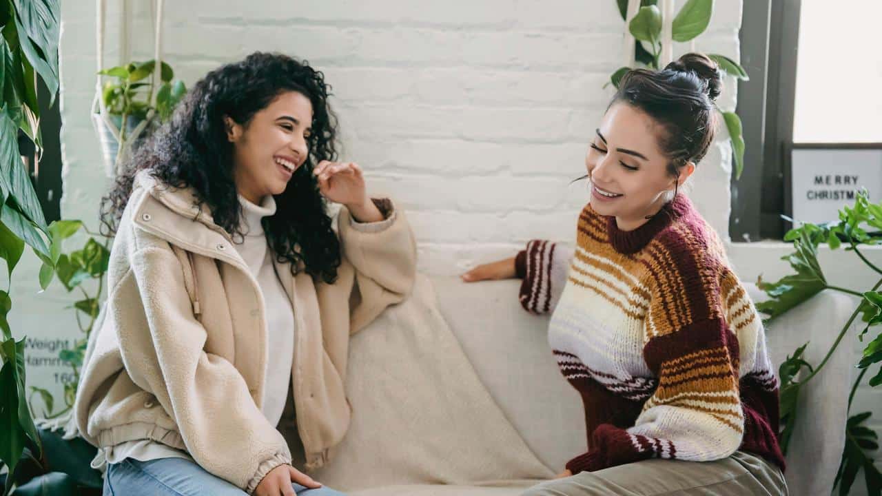A pair of people sitting on a couch laughing together.