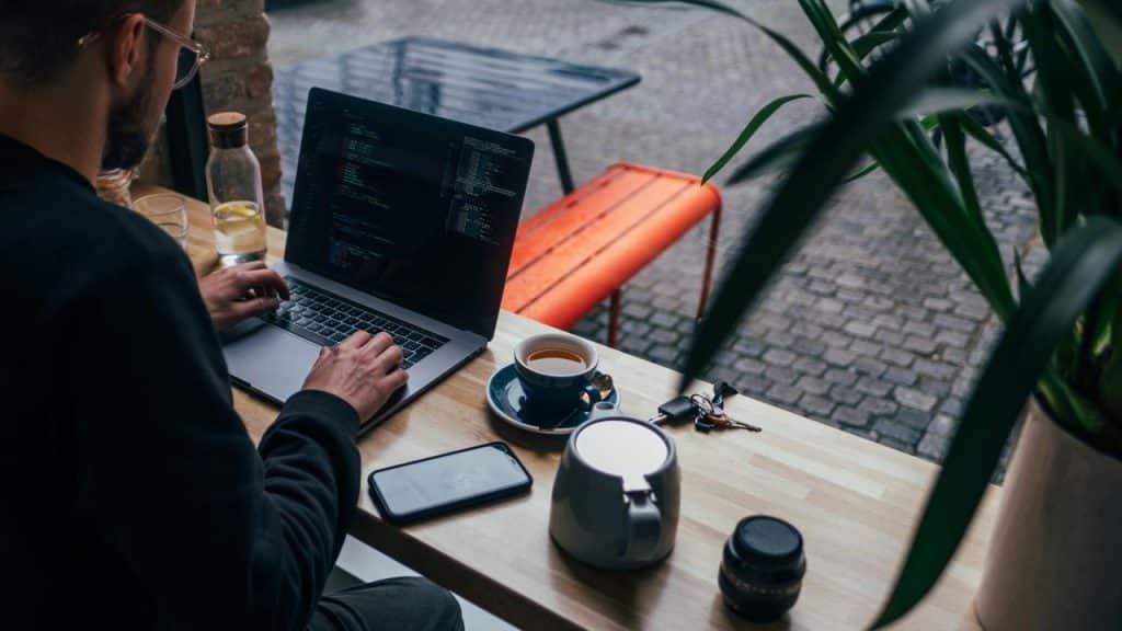 A person working on a laptop at a café table with coffee nearby.