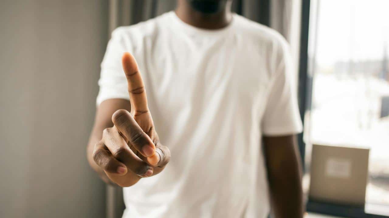 A person holding up one finger indoors.