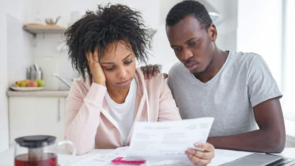 A man and woman looking down at papers together with focused and serious expressions.