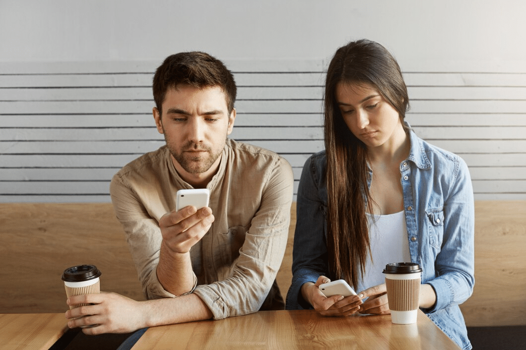 Young couple sitting at table checking phones