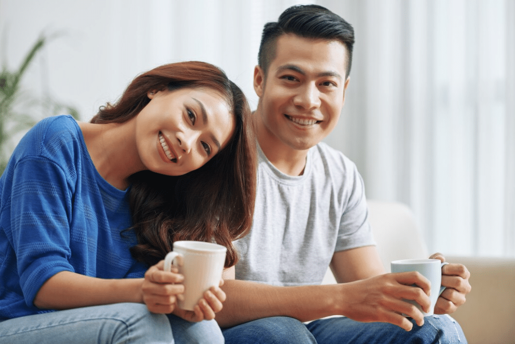Happy young couple having coffee sitting on couch