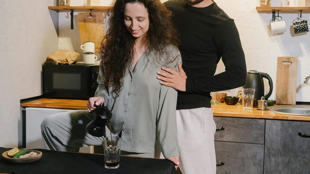 A couple making coffee together in a kitchen.