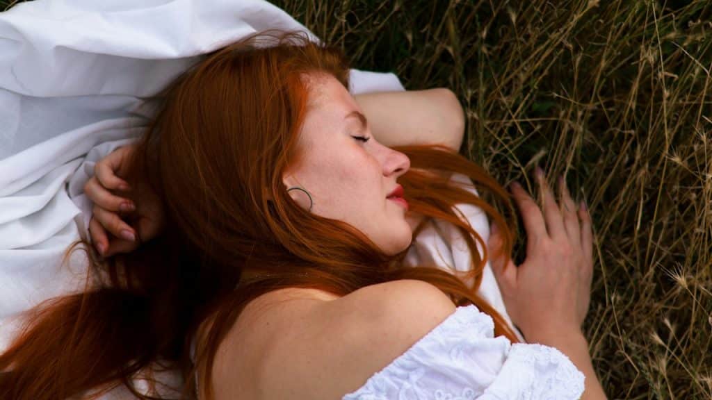 A woman lying on the grass with her eyes closed.