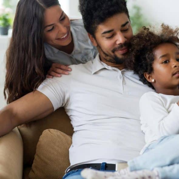 A relaxed family sitting together on a couch at home.