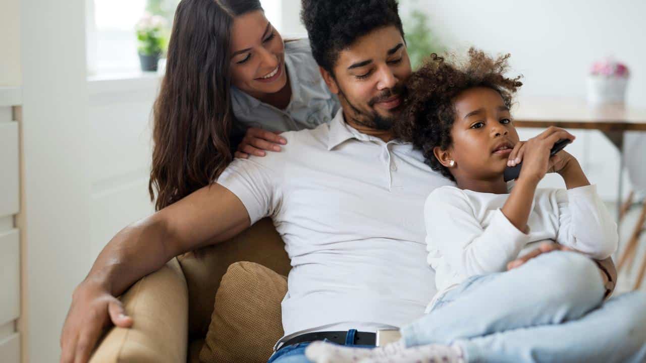 A relaxed family sitting together on a couch at home.