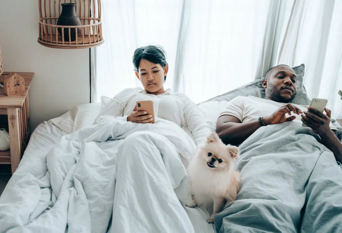 Couple in bed using phones