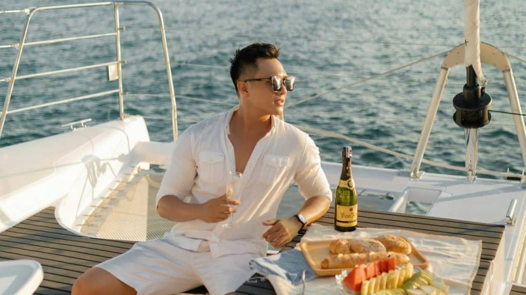 A man relaxing on a boat with a drink and snacks.