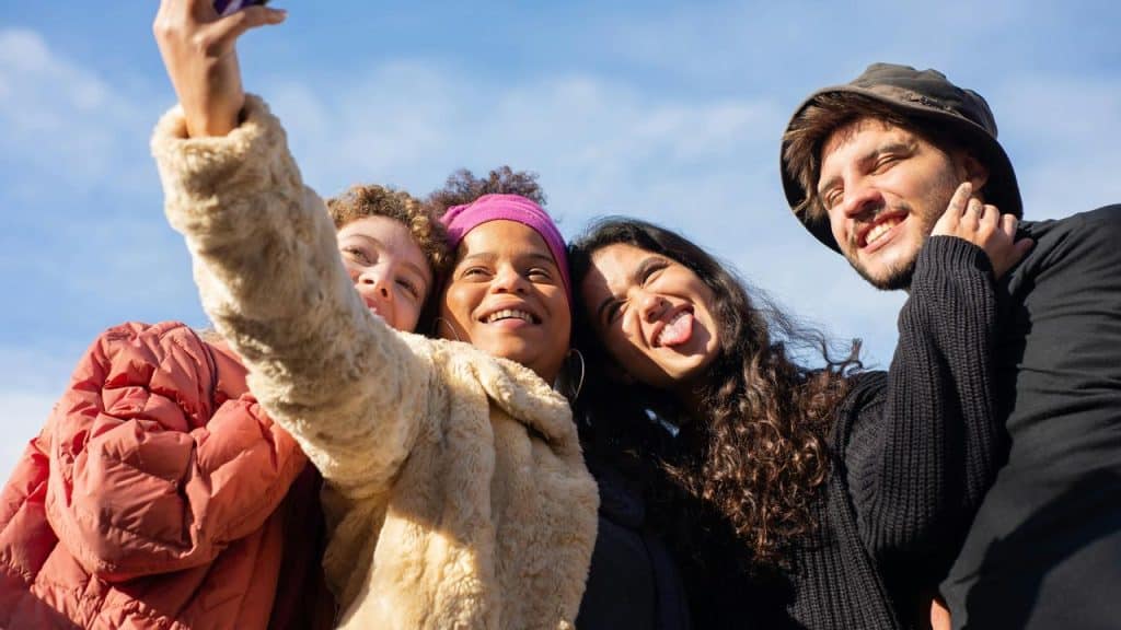 A group of friends taking a selfie outdoors and smiling