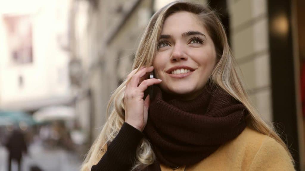 A woman smiling while talking on a phone outdoors