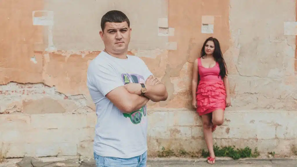 A man and a woman standing against a wall.