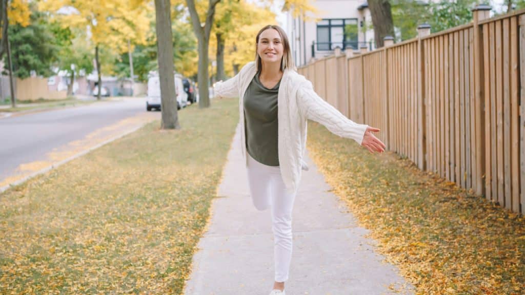 A woman walking on a road in fall season.