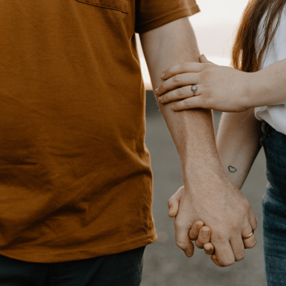 A close up of a couple holding their hands.