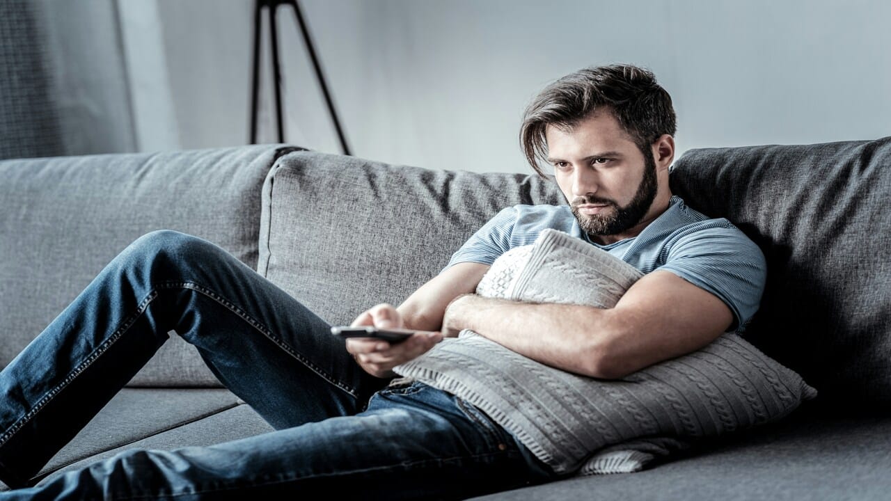 A man looking upset while watching TV