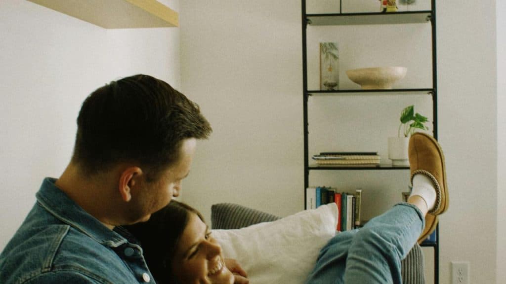 A couple relaxing together on a couch, smiling.