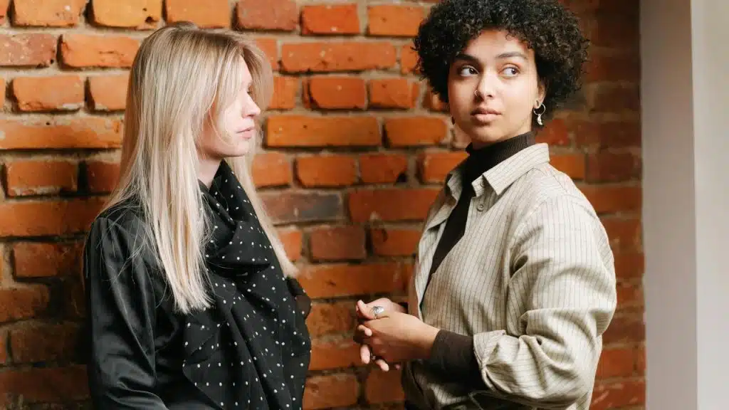 A pair of women standing in front of a brick wall.