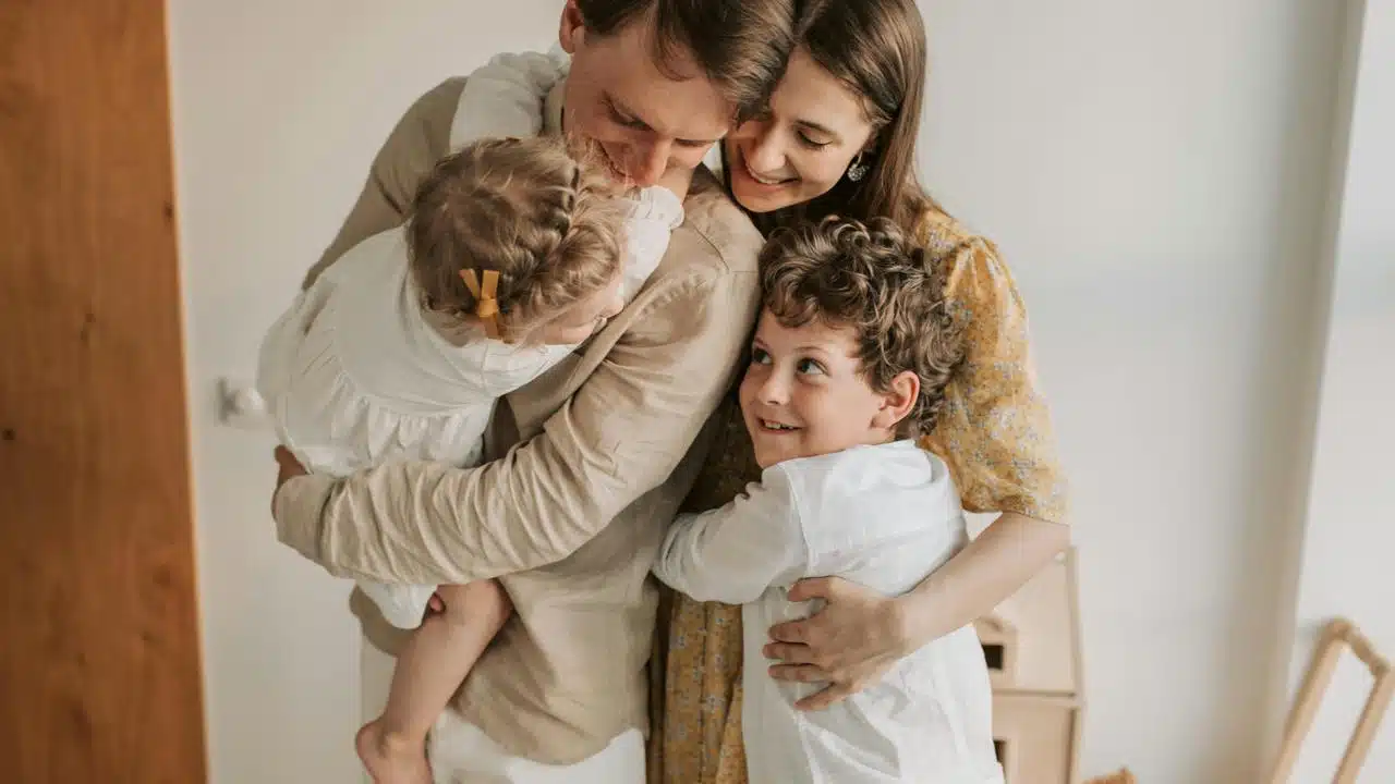 A family hugging and smiling together at home.