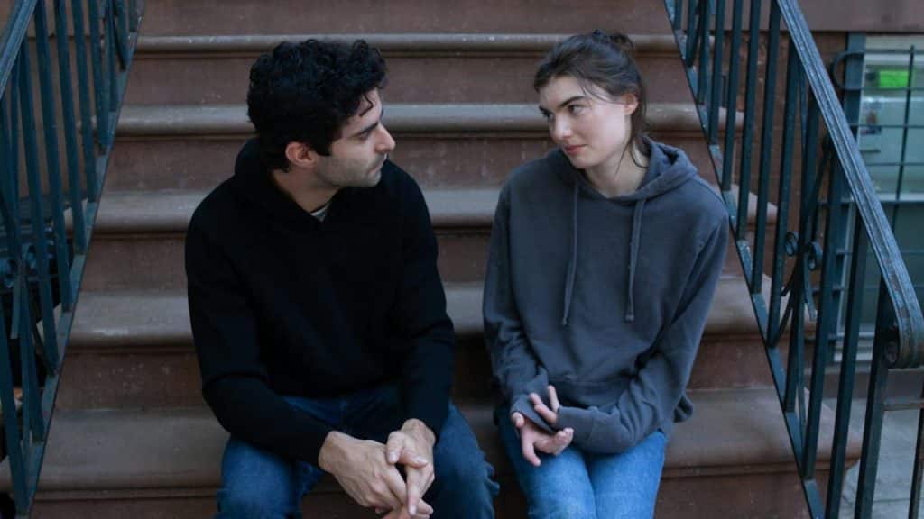 A couple sitting on stairs looking at each other.