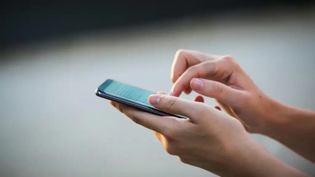 A person using a smartphone and typing on the screen.