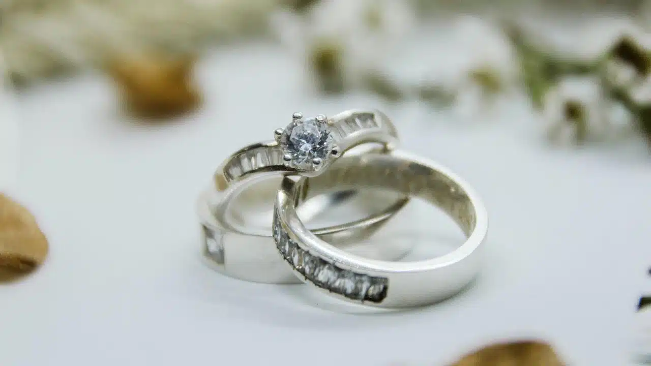 A close-up of two silver rings with a diamond centerpiece.