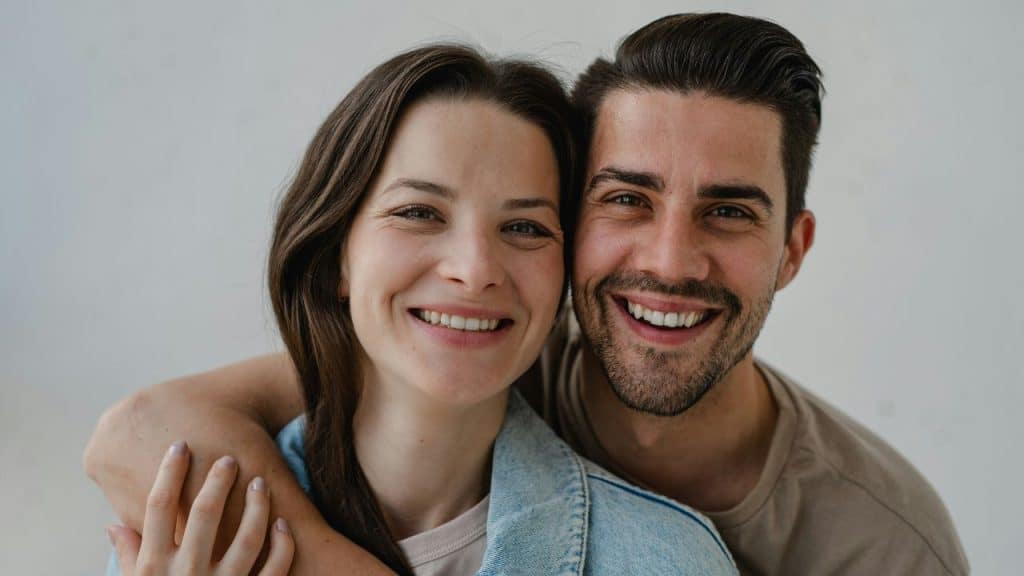 A close-up portrait of a smiling man and woman with their heads leaning together.
