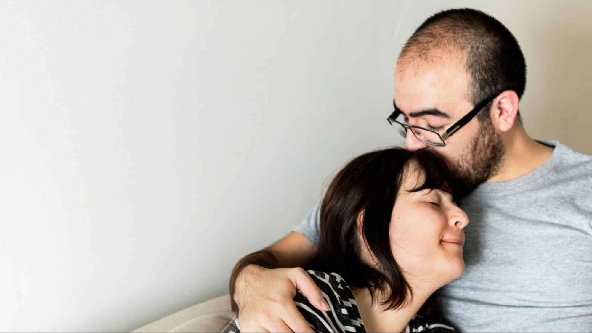 A man kissing woman’s head