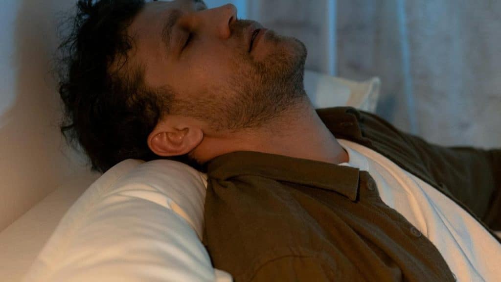 A man resting with eyes closed on a pillow indoors.