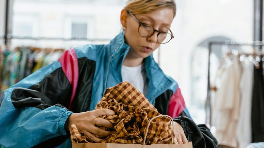 A woman looking through clothes in a shopping bag.