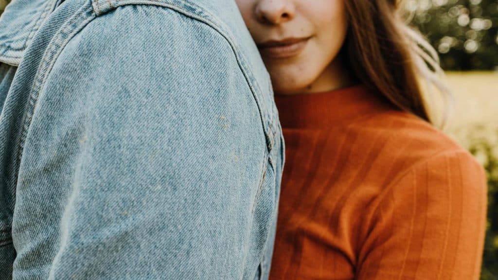 A woman leaning close to someone wearing a denim jacket.