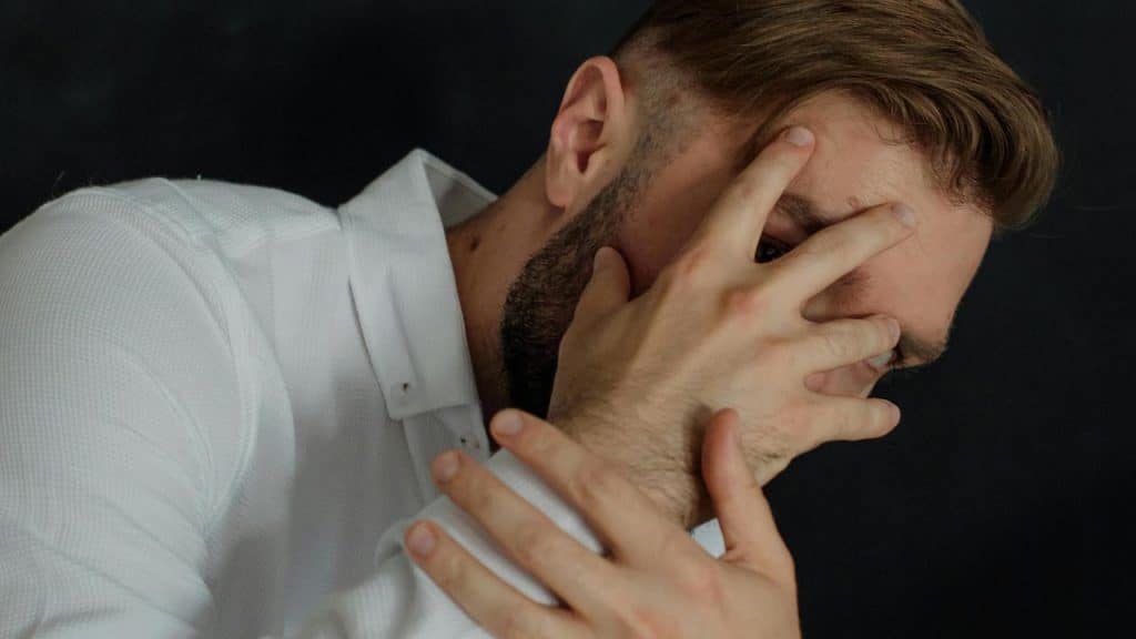 A man covering his face with his hand, appearing stressed or upset.