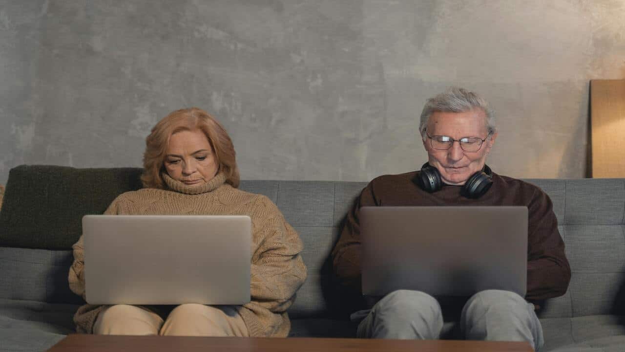 A couple sitting on the sofa using their laptops