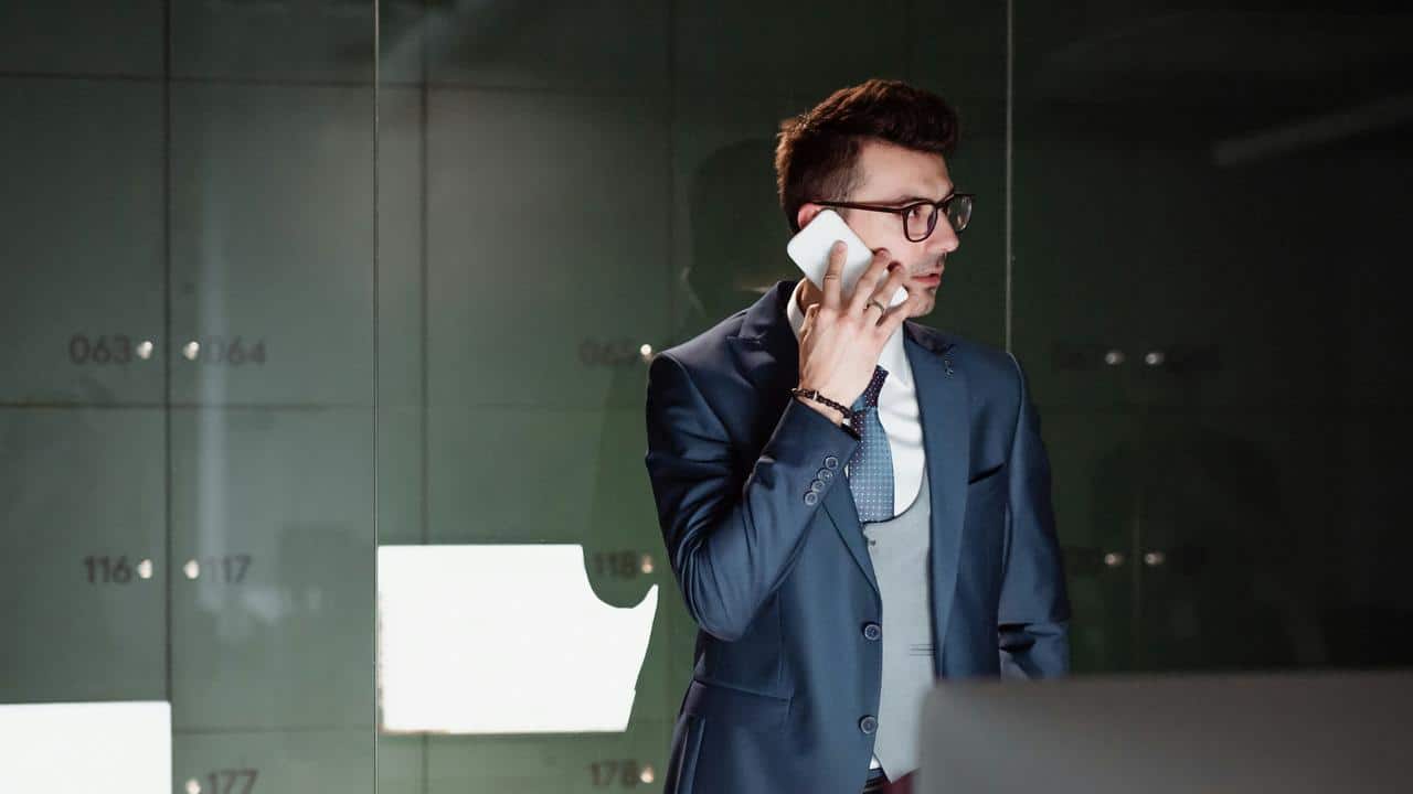 A man in a suit talking on a smartphone in a modern office.