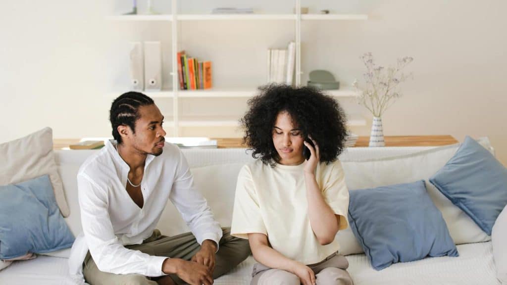 A woman on the phone sitting beside a man on a couch.
