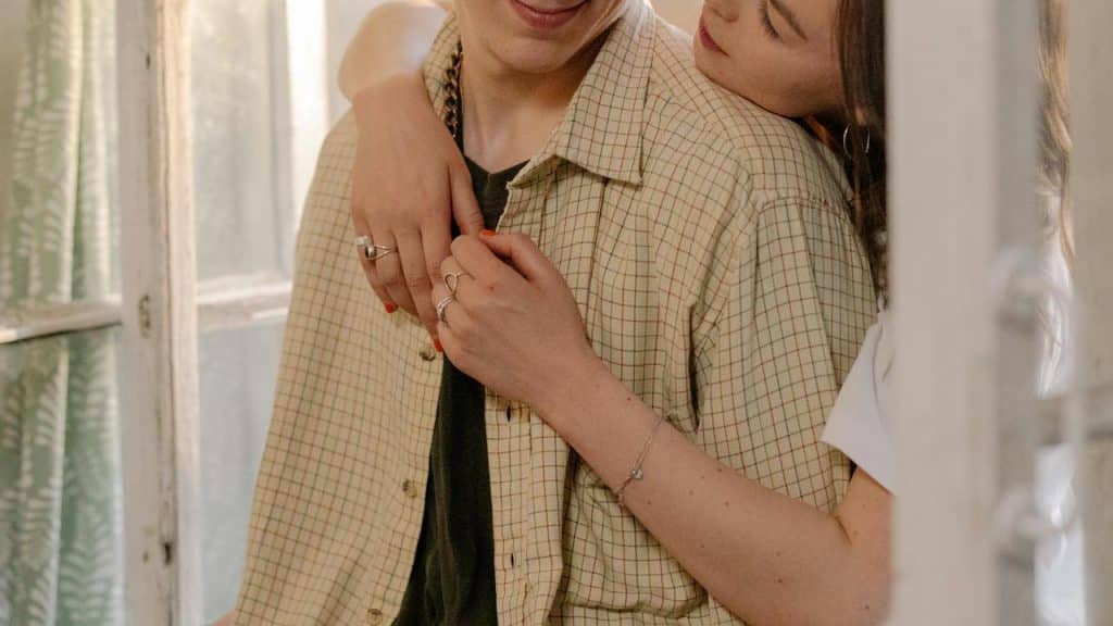 A woman hugging a man from behind with her head resting on his shoulder