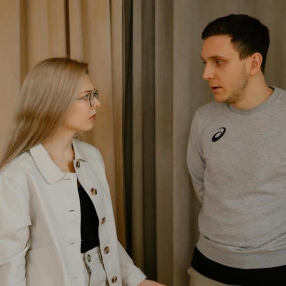A man and woman having a serious conversation indoors.